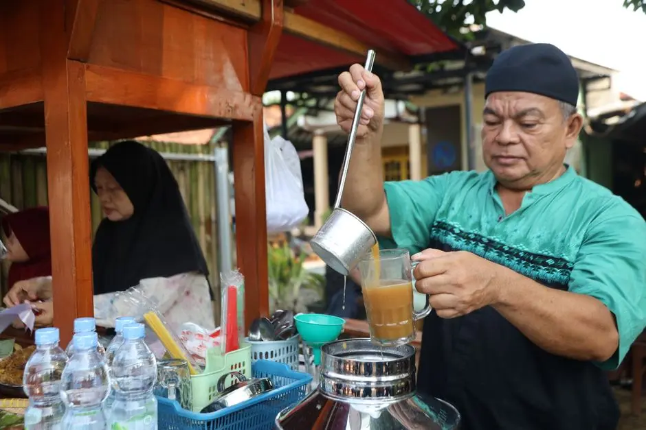 Penjual menyiapkan jajanan tradisional di tempat makan sederhana